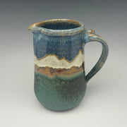 Stoneware pitcher with blue and green glaze and a mountain