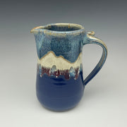Blue ceramic pitcher with the image of a mountain on it