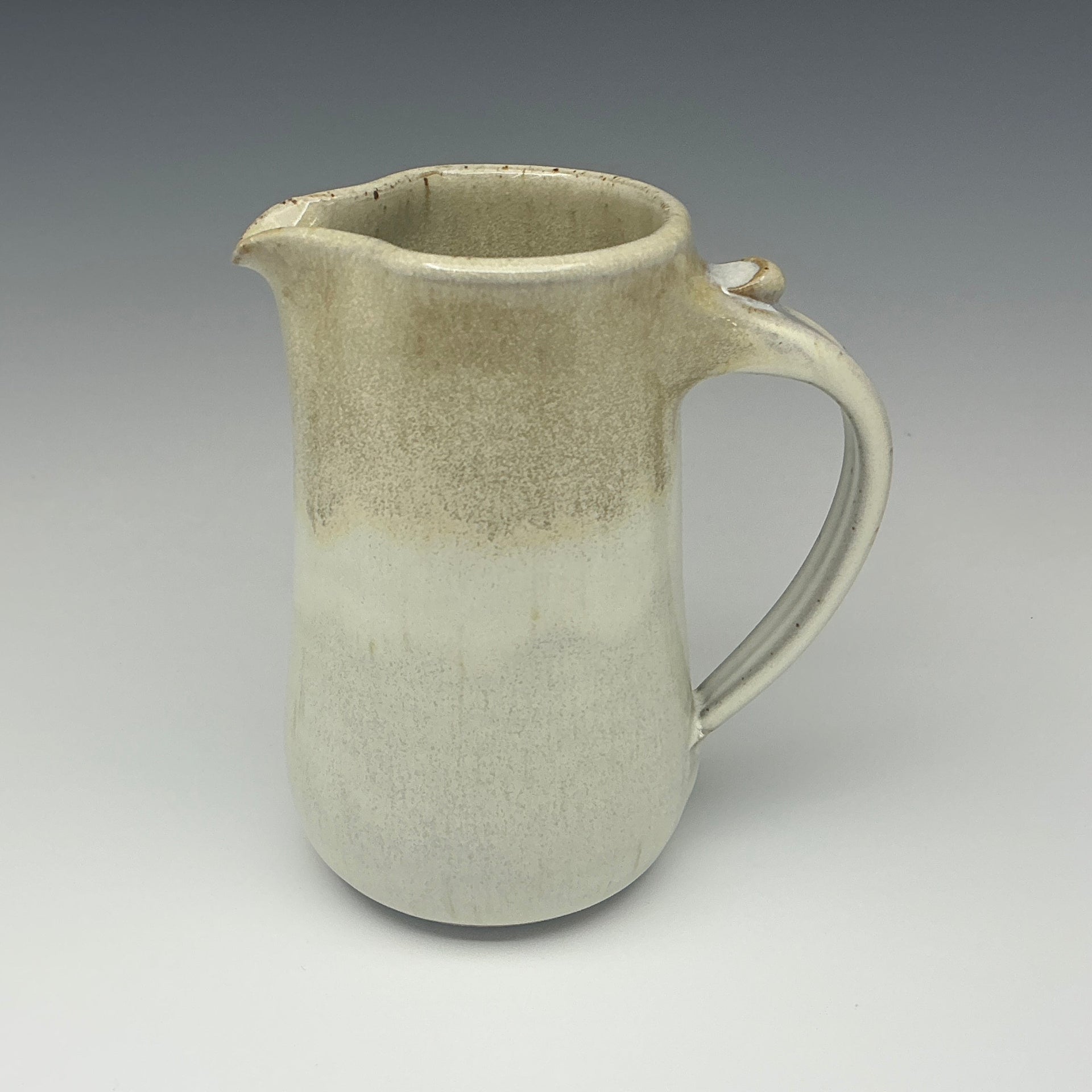 Ceramic pitcher in off white on a gray background