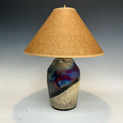 Table lamp with a textured ceramic base and brown lampshade on a gradient background