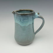Teal ceramic pitcher on a gray background