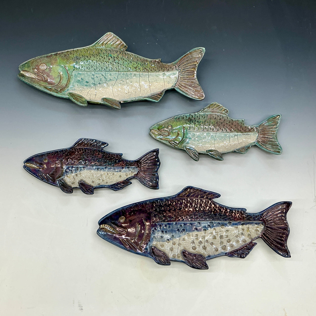 Four ceramic fish sculptures on a gray background