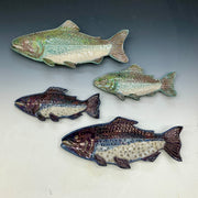 Four ceramic fish sculptures on a gray background