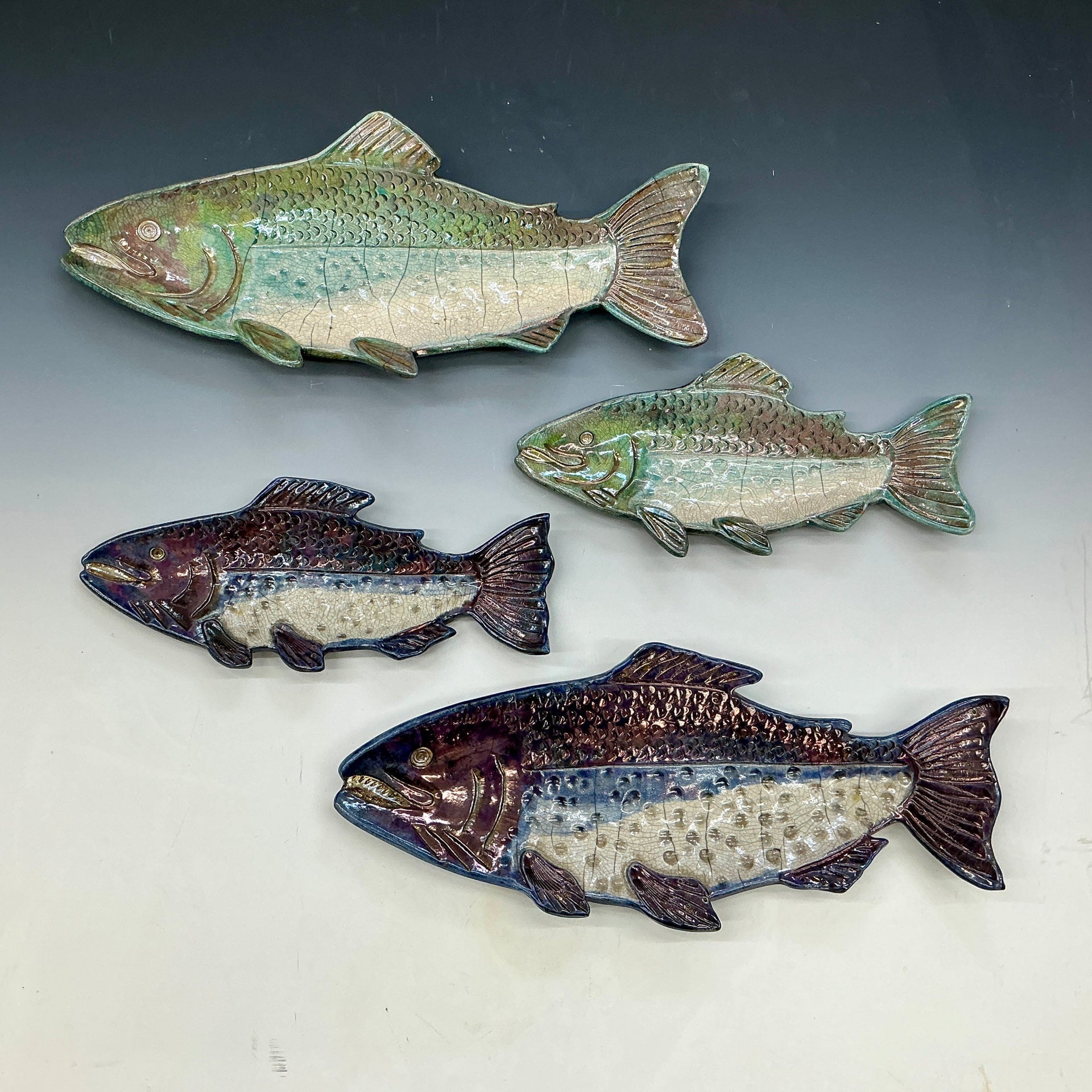 Four ceramic fish sculptures on a gray background