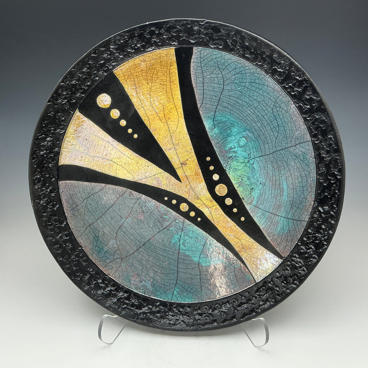 Decorative ceramic plate with abstract design on a stand against a gray background