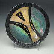 a Raku wall plate with an abstract image in gold teal and black