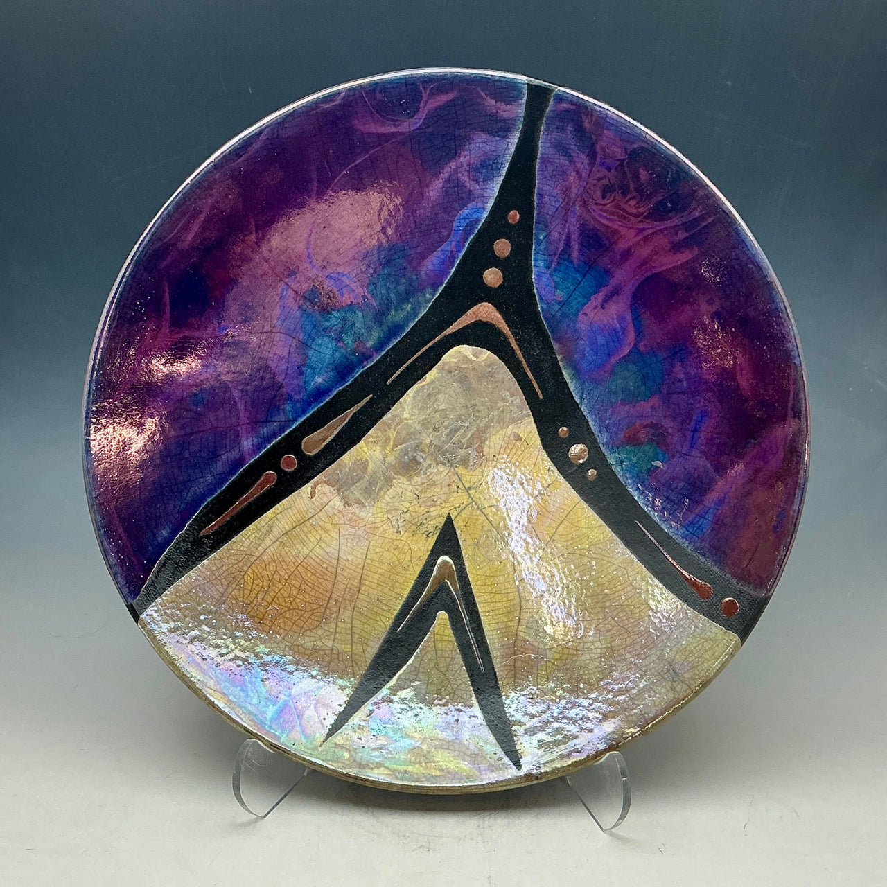 Decorative plate with a peace symbol design on a stand against a dark background