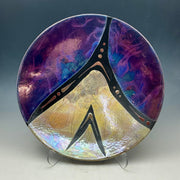 Decorative plate with a peace symbol design on a stand against a dark background