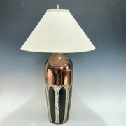 Table lamp with a decorative ceramic base of aspen trees on it and white shade on a gray background