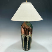 Table lamp with a textured copper base with aspen trees and white shade on a gradient background