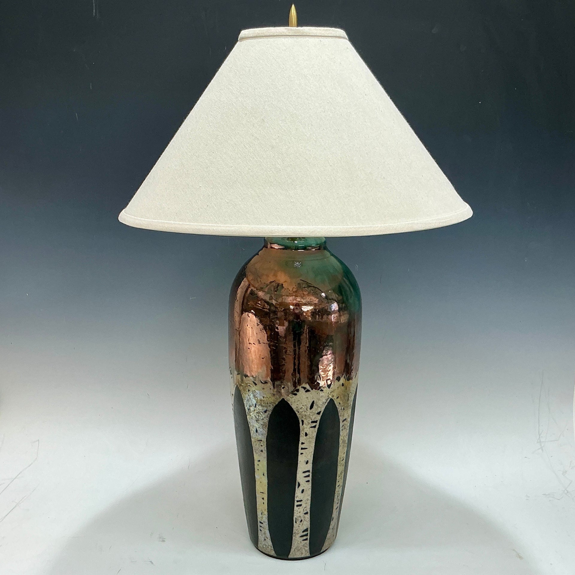 Table lamp with a textured copper base with aspen trees and white shade on a gradient background