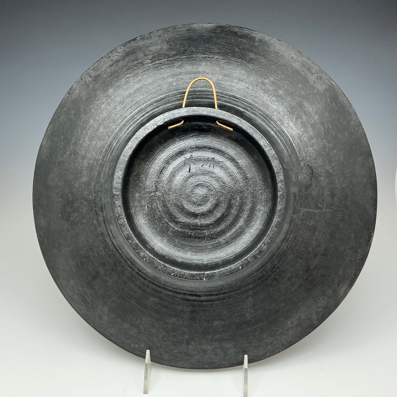 Black ceramic plate with concentric circle design on a gray background