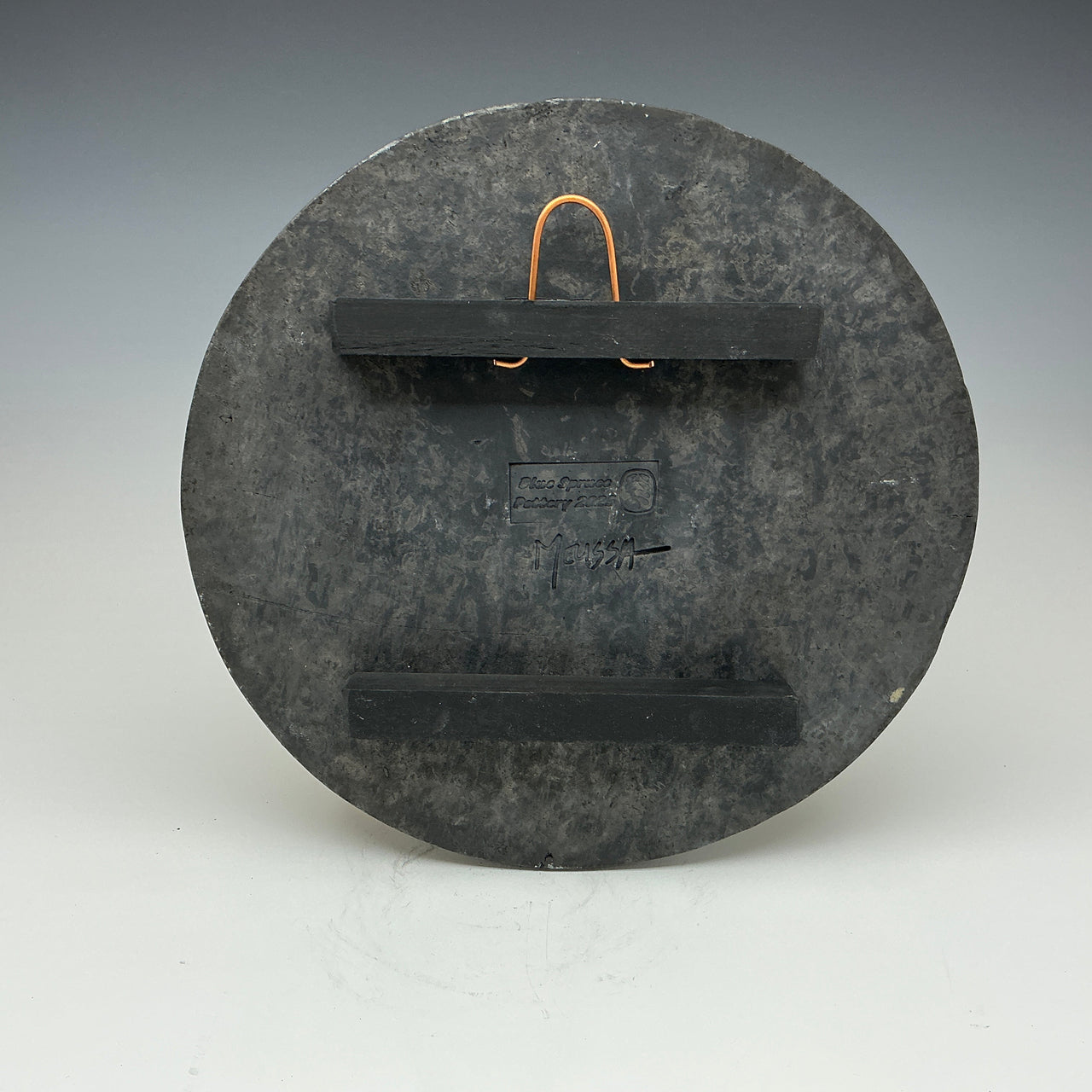 Back of the round wall tile showing the hanger