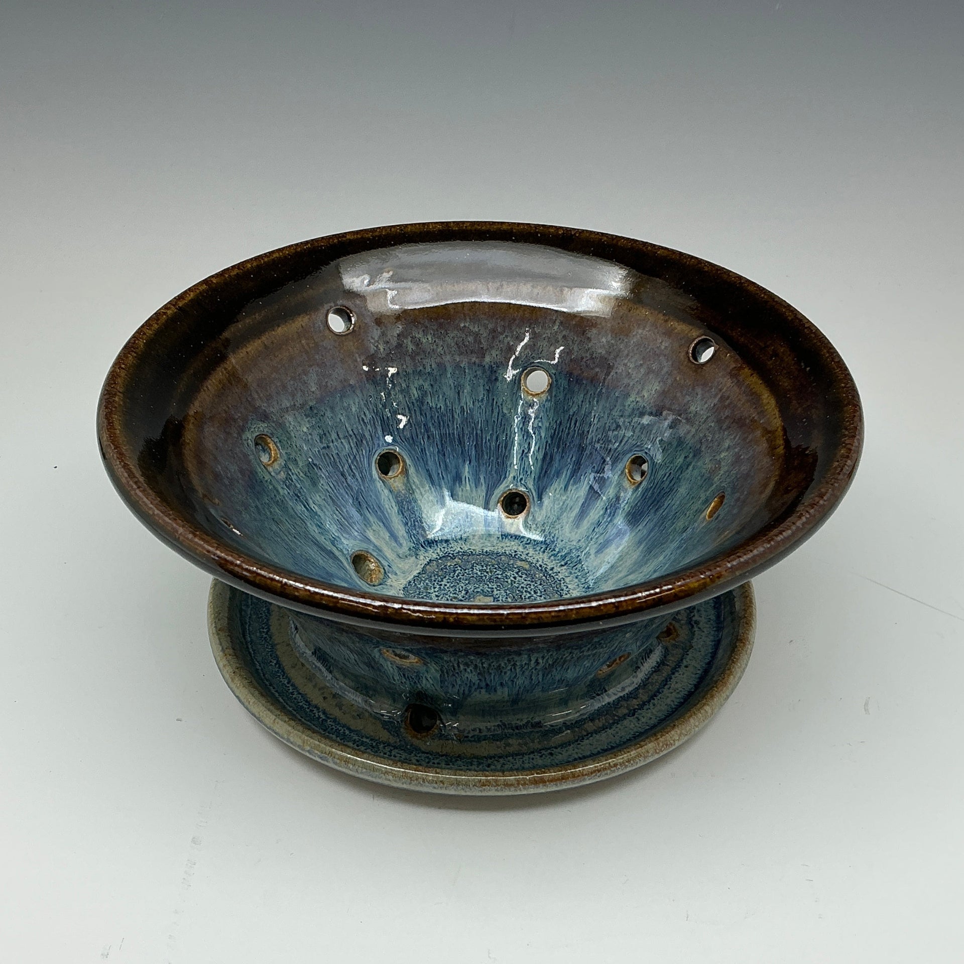 Ceramic strainer with blue glaze on a white background
