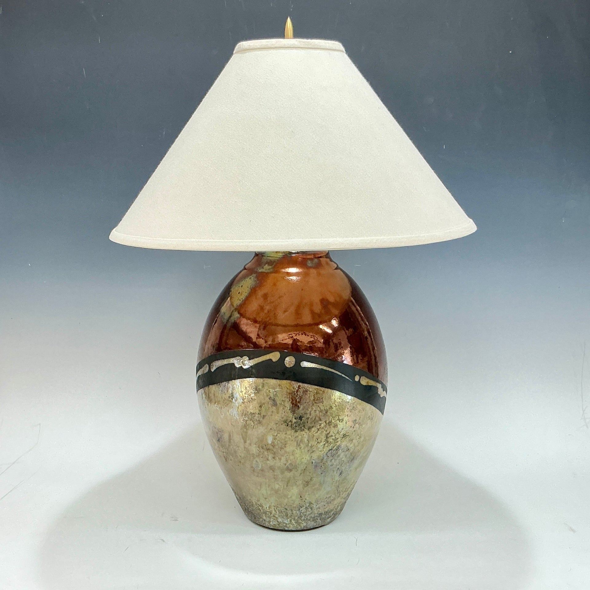 Table lamp with a decorative base and white shade on a gray background