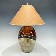 Table lamp with a textured brown base and beige lampshade on a gradient background