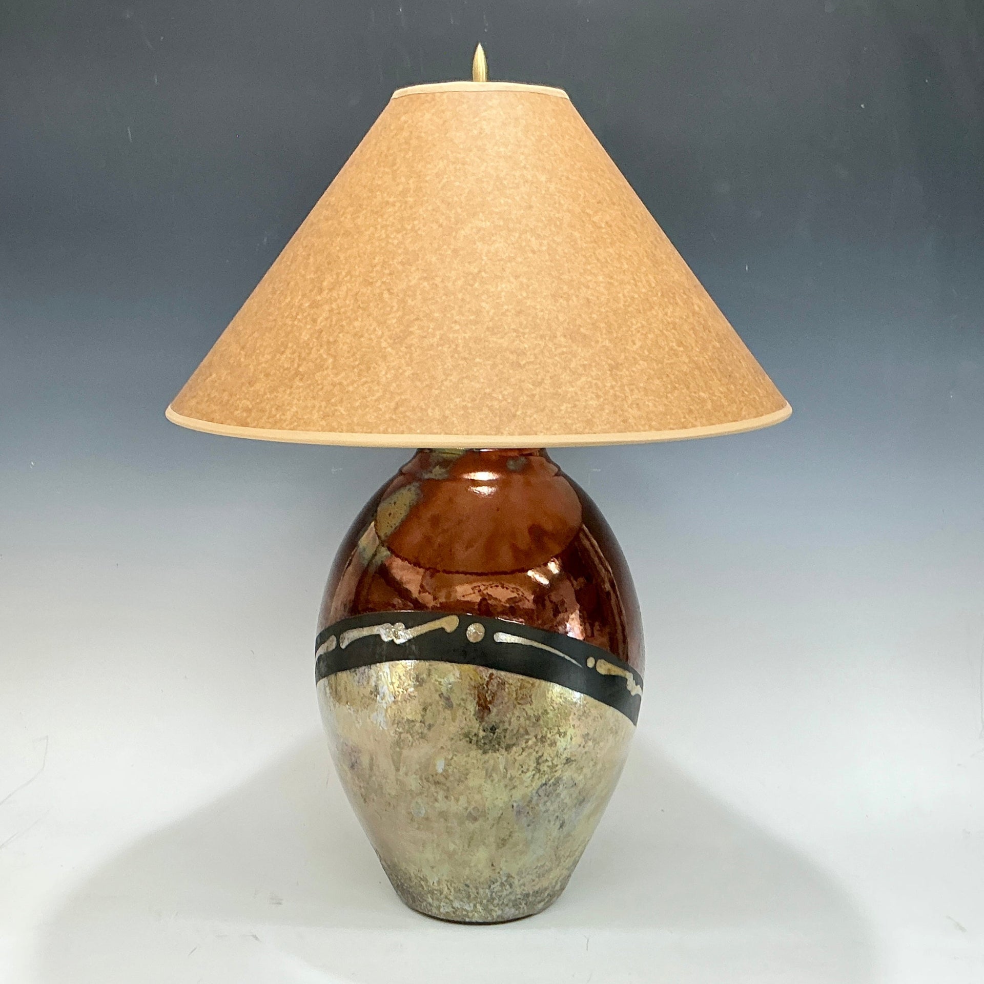 Table lamp with a textured brown base and beige lampshade on a gradient background