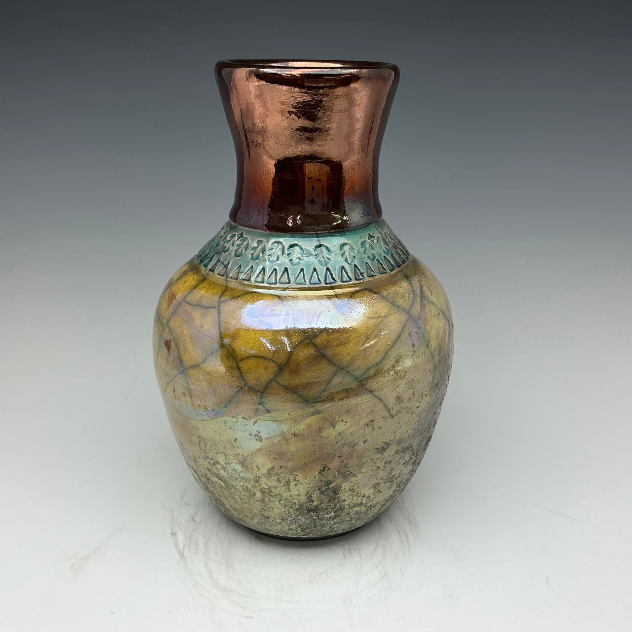 Raku vase in copper and gold colors with a  teal leaf accent deign around the neck