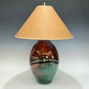 Decorative lamp with a brown and green base and a beige lampshade on a gray background