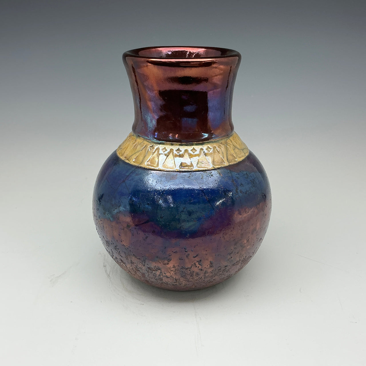 raku vase in dark blue and copper glazes with a gold band around the neck