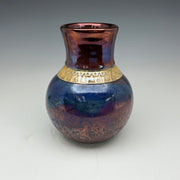 raku vase in dark blue and copper glazes with a gold band around the neck