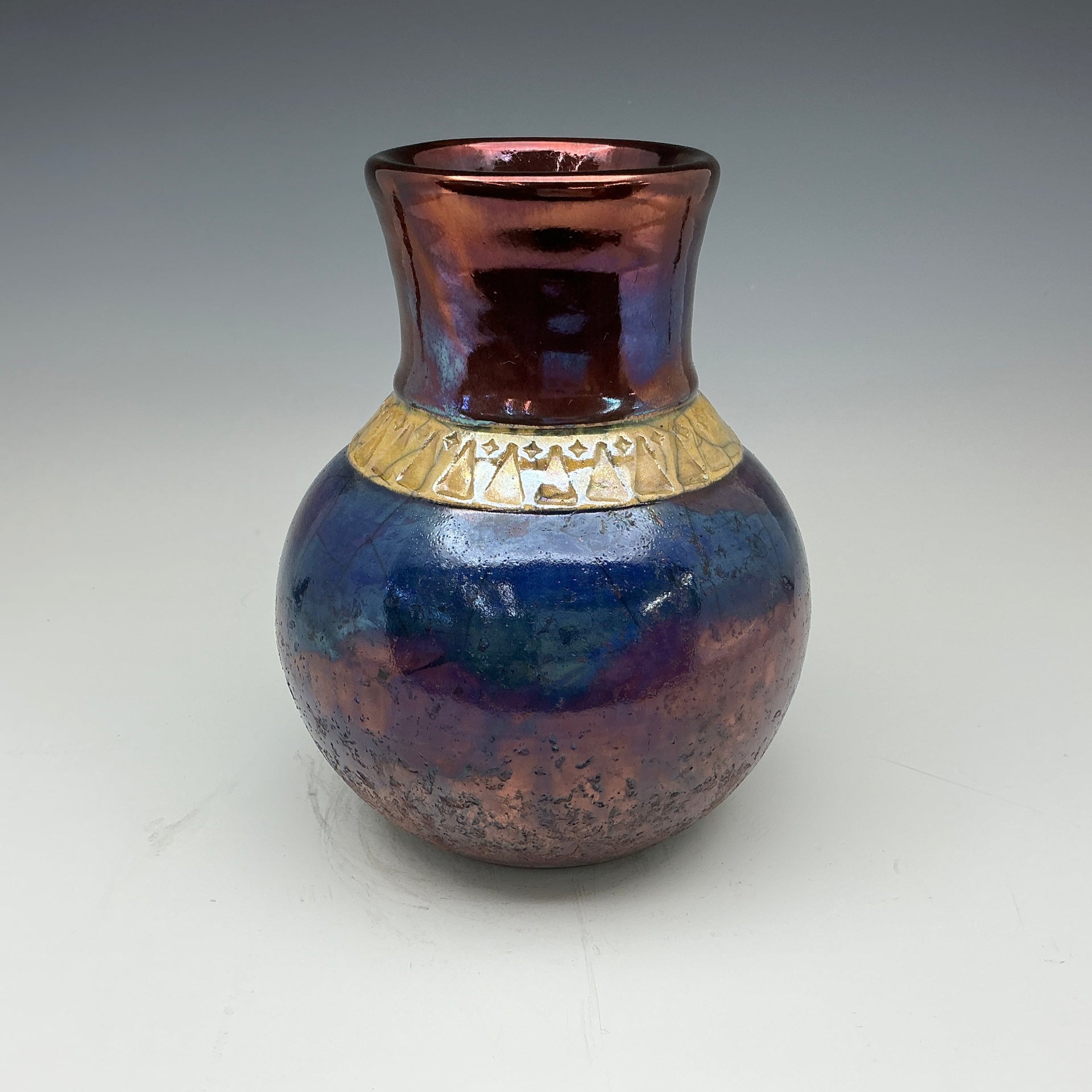 raku vase in dark blue and copper glazes with a gold band around the neck