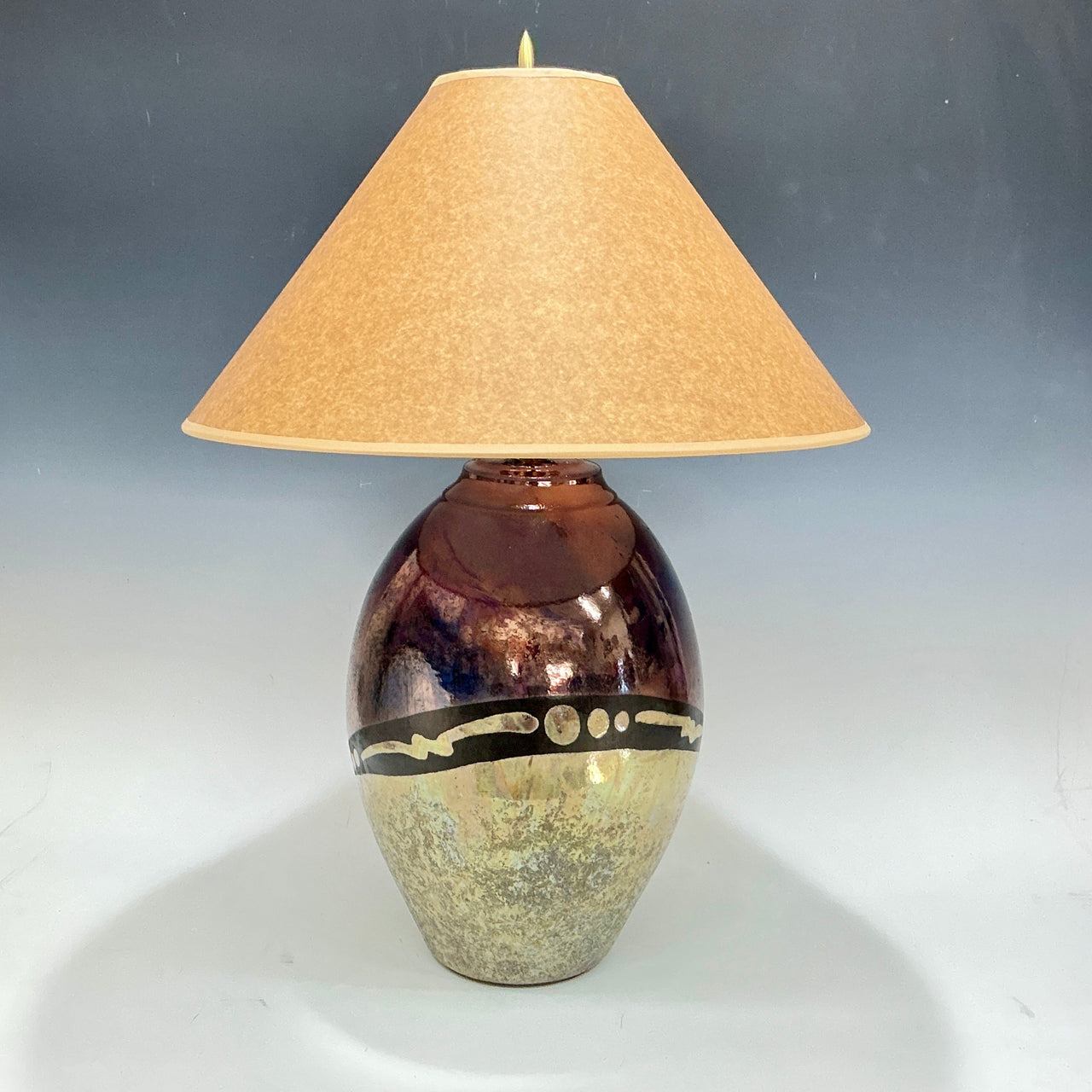 Decorative lamp with a textured base and beige shade on a gray background