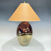 Decorative lamp with a textured base and beige shade on a gray background