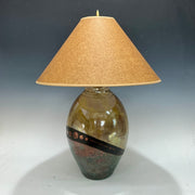 Decorative lamp in gold and teal with a textured shade on a gray background