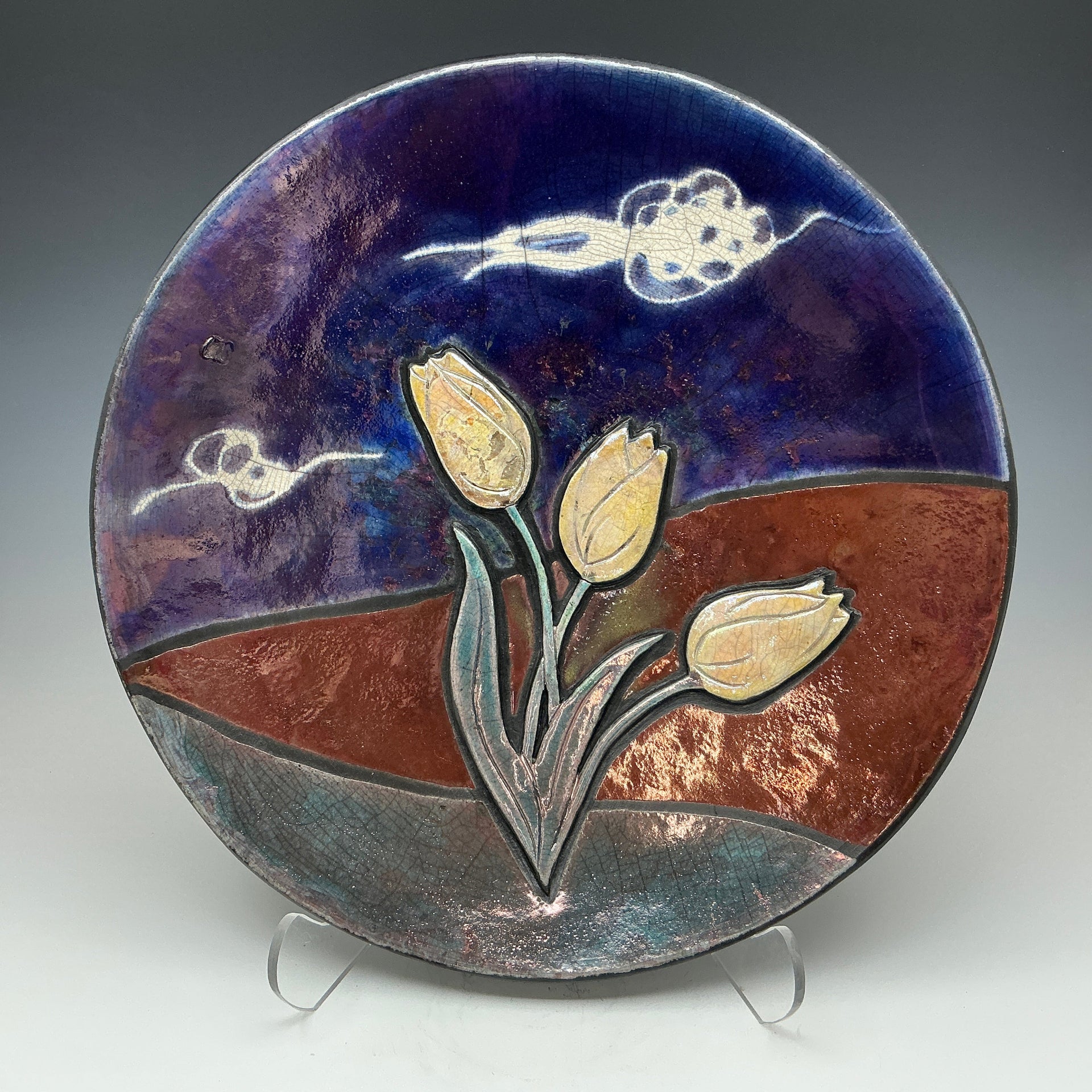 Ceramic Raku plate with tulip on a grey backfround