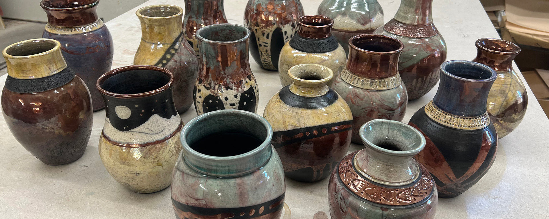 Collection of ceramic vases with various designs on a white surface