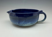 Blue ceramic pitcher on a gray background