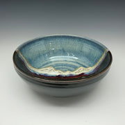 Stack of ceramic bowls with blue and black glaze on a gray background
