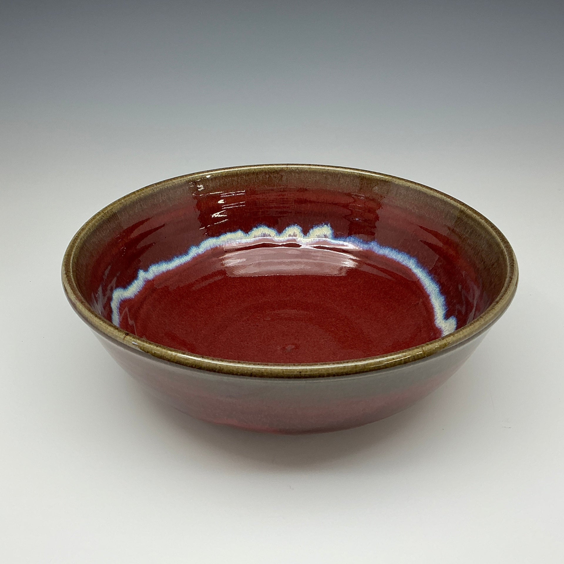 Red ceramic bowl with a glossy surface on a gray background