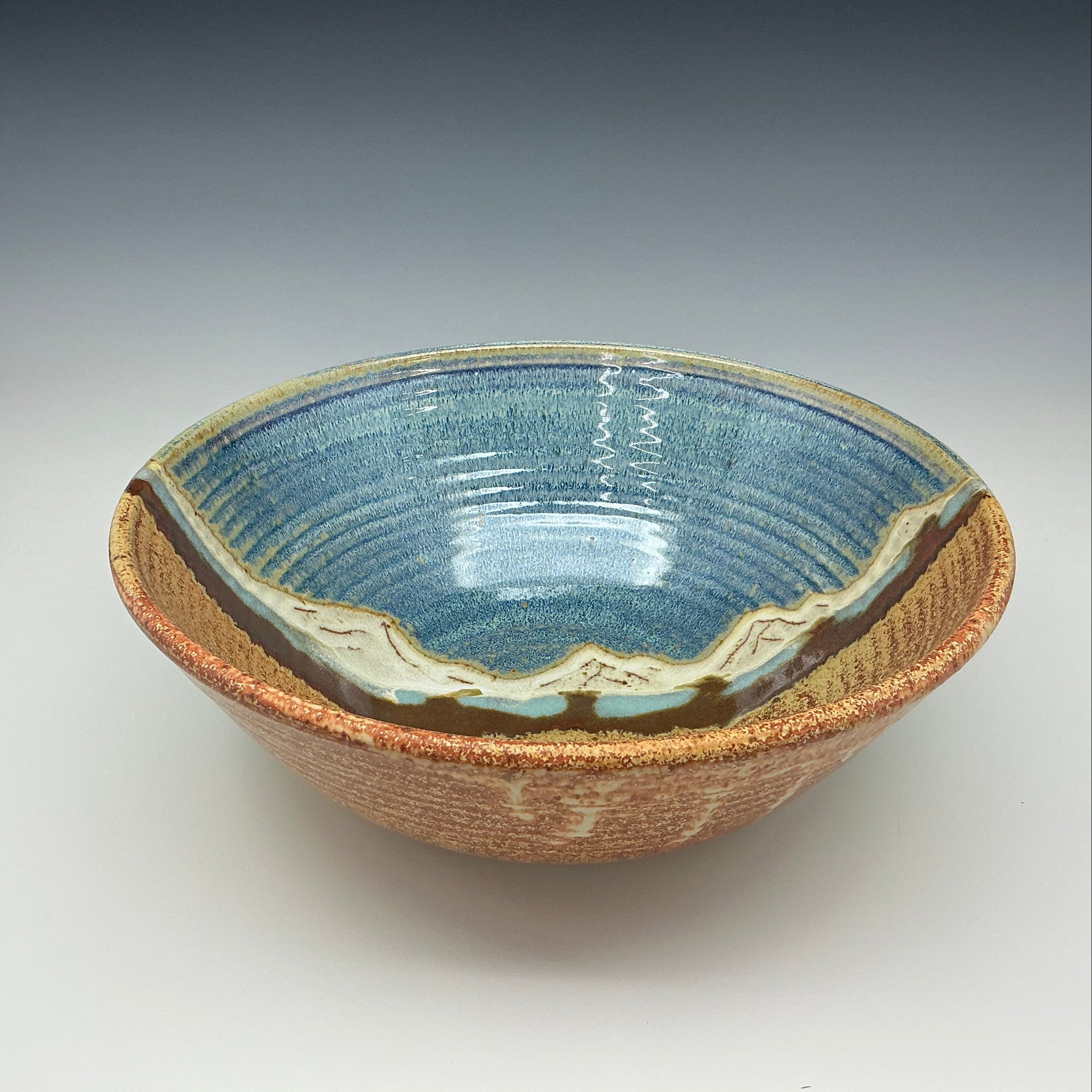 Ceramic bowl with blue interior and brown exterior on a gray background