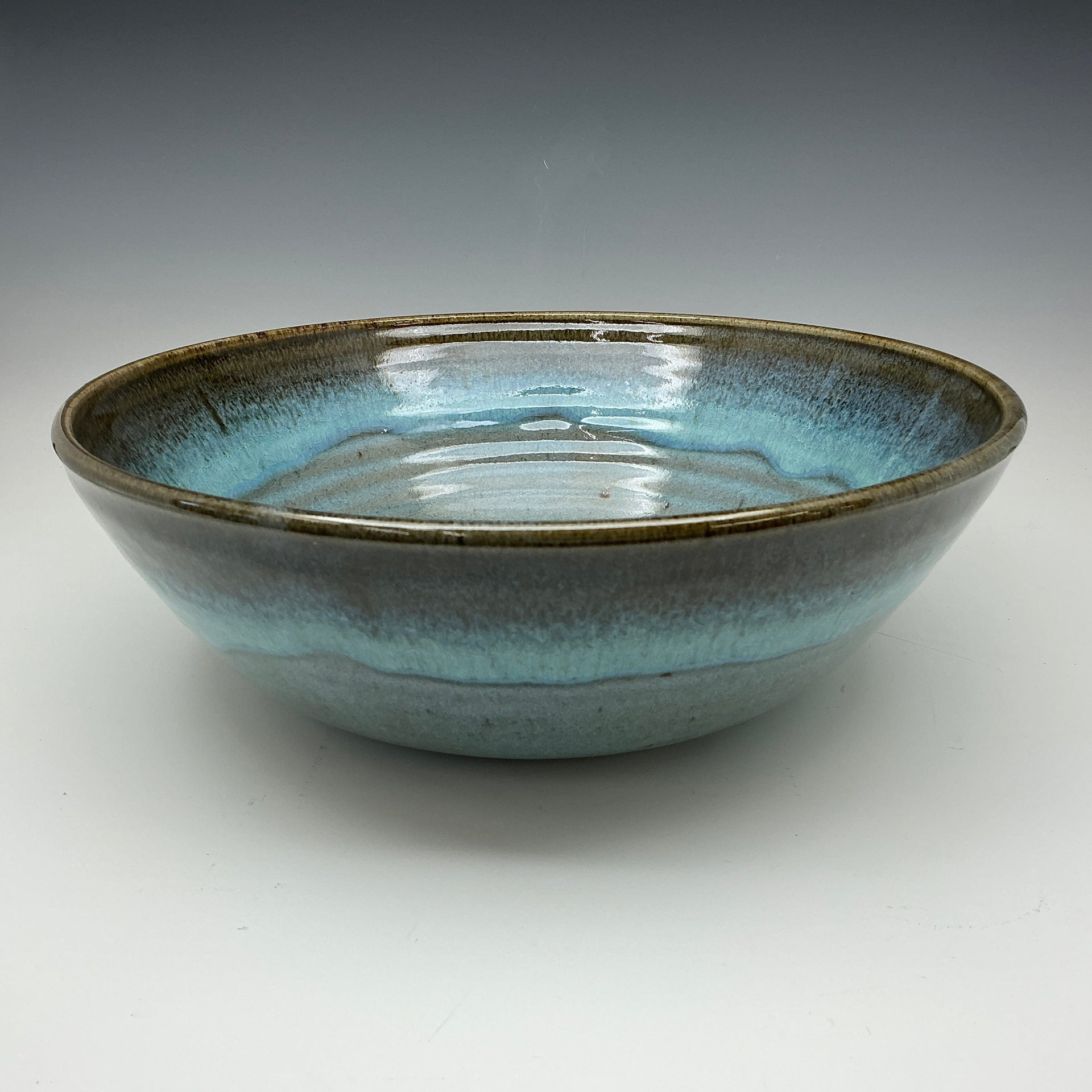 Ceramic bowl with blue and black glaze on a gray background