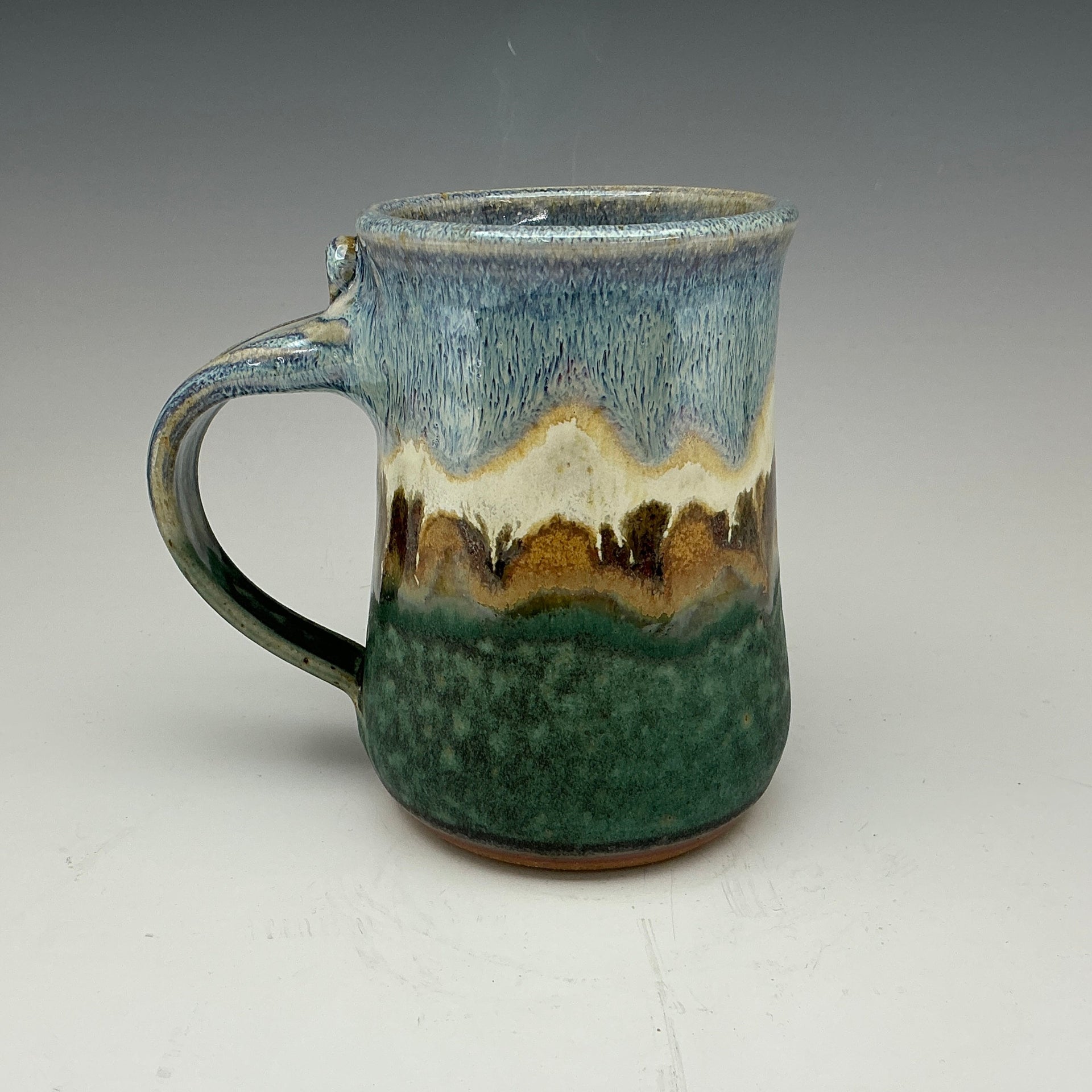 large mug in green and blue with a mountain on it.