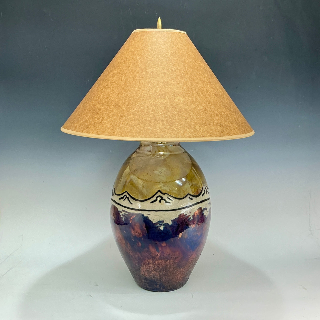 Decorative lamp with mountains and a brown shade on a plain background