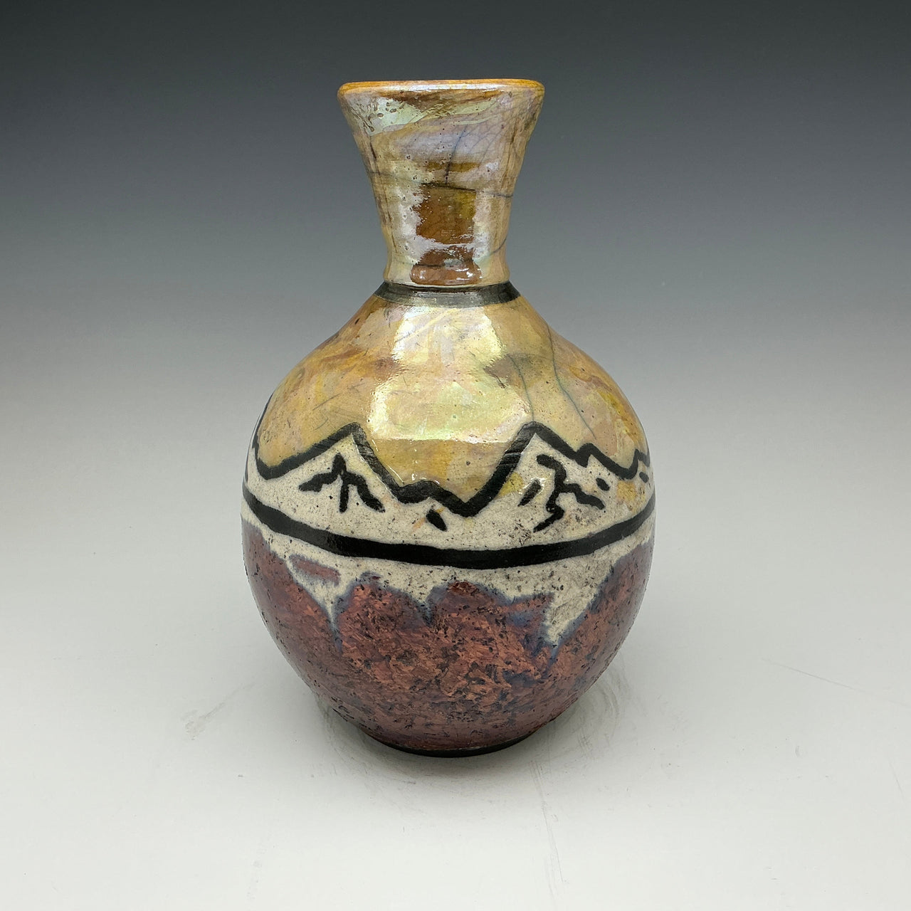 raku vase with mountains on it in gold and copper colors