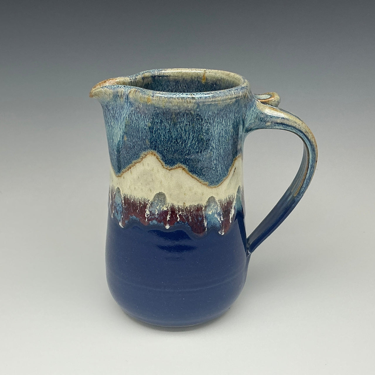 Blue ceramic pitcher with the image of a mountain on it