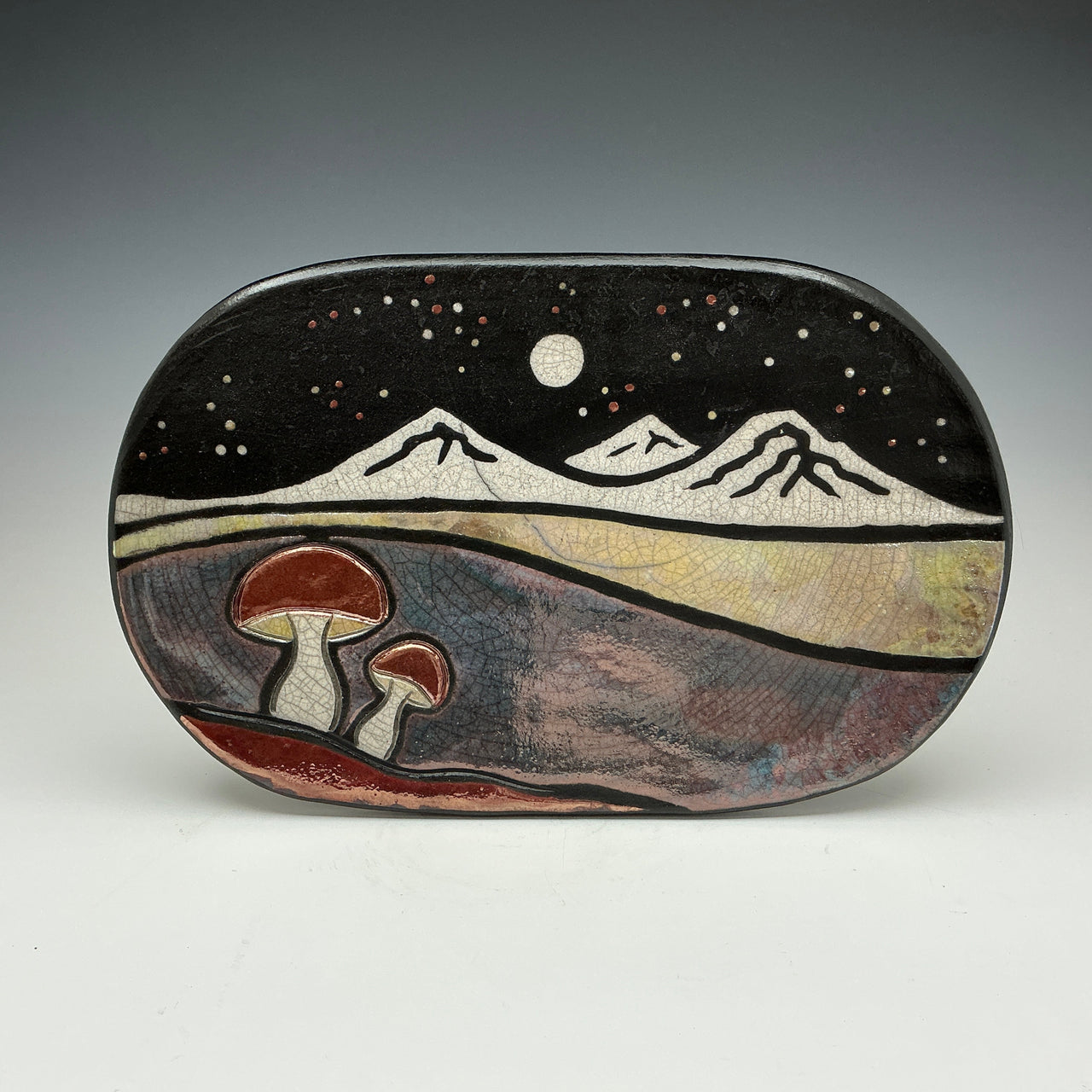 Decorative stone with mountain and mushroom design on a gray background