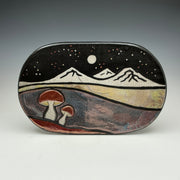Decorative stone with mountain and mushroom design on a gray background