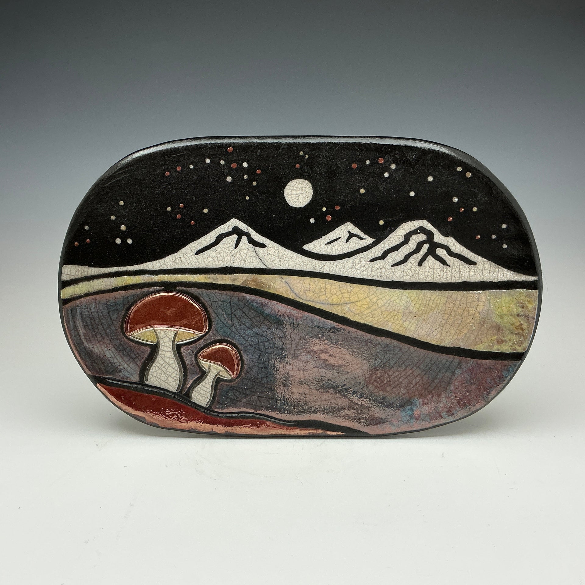 Decorative stone with mountain and mushroom design on a gray background
