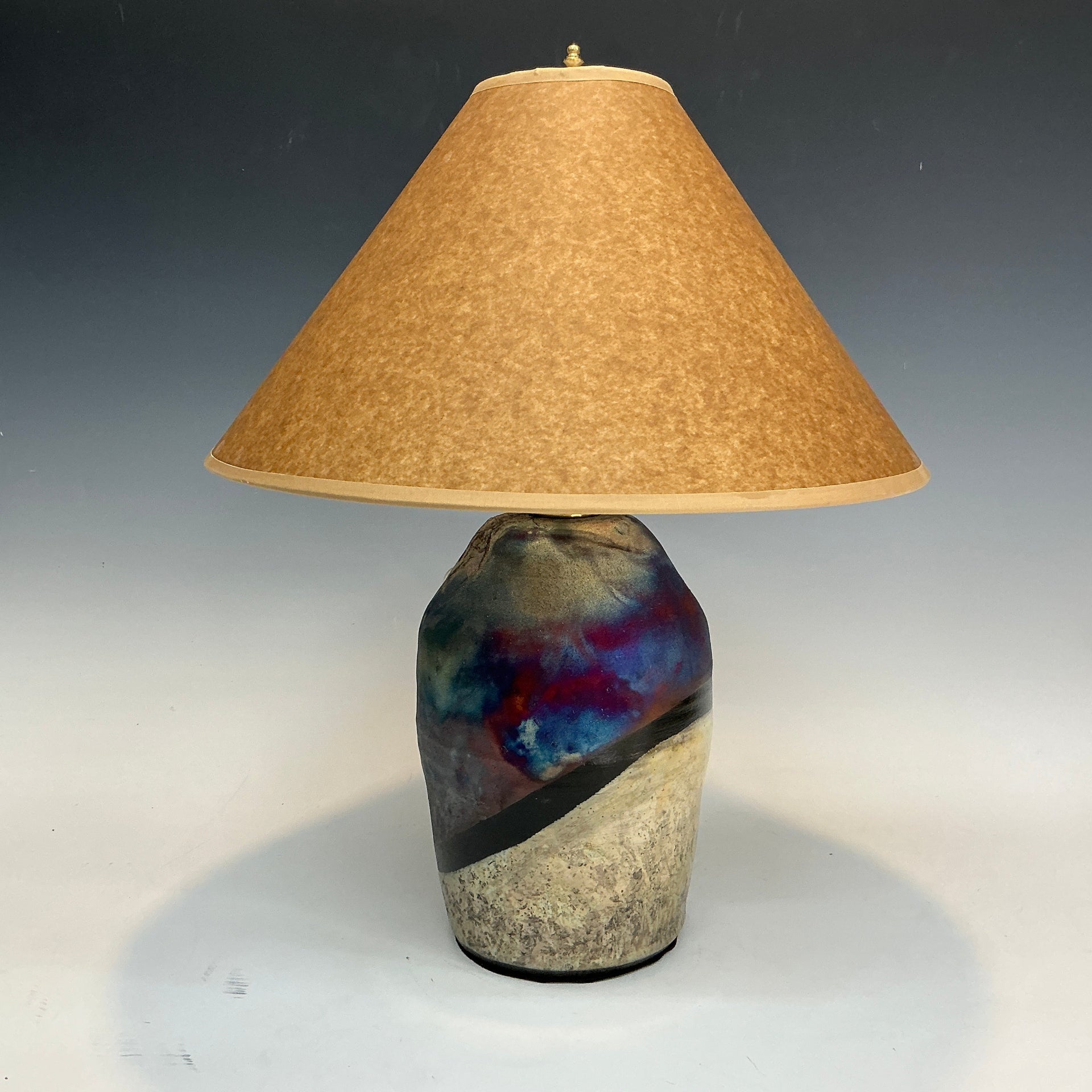 Table lamp with a textured ceramic base and brown lampshade on a gradient background