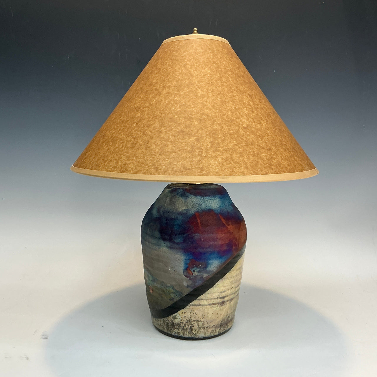 Table lamp with a textured ceramic base and beige lampshade on a gradient background