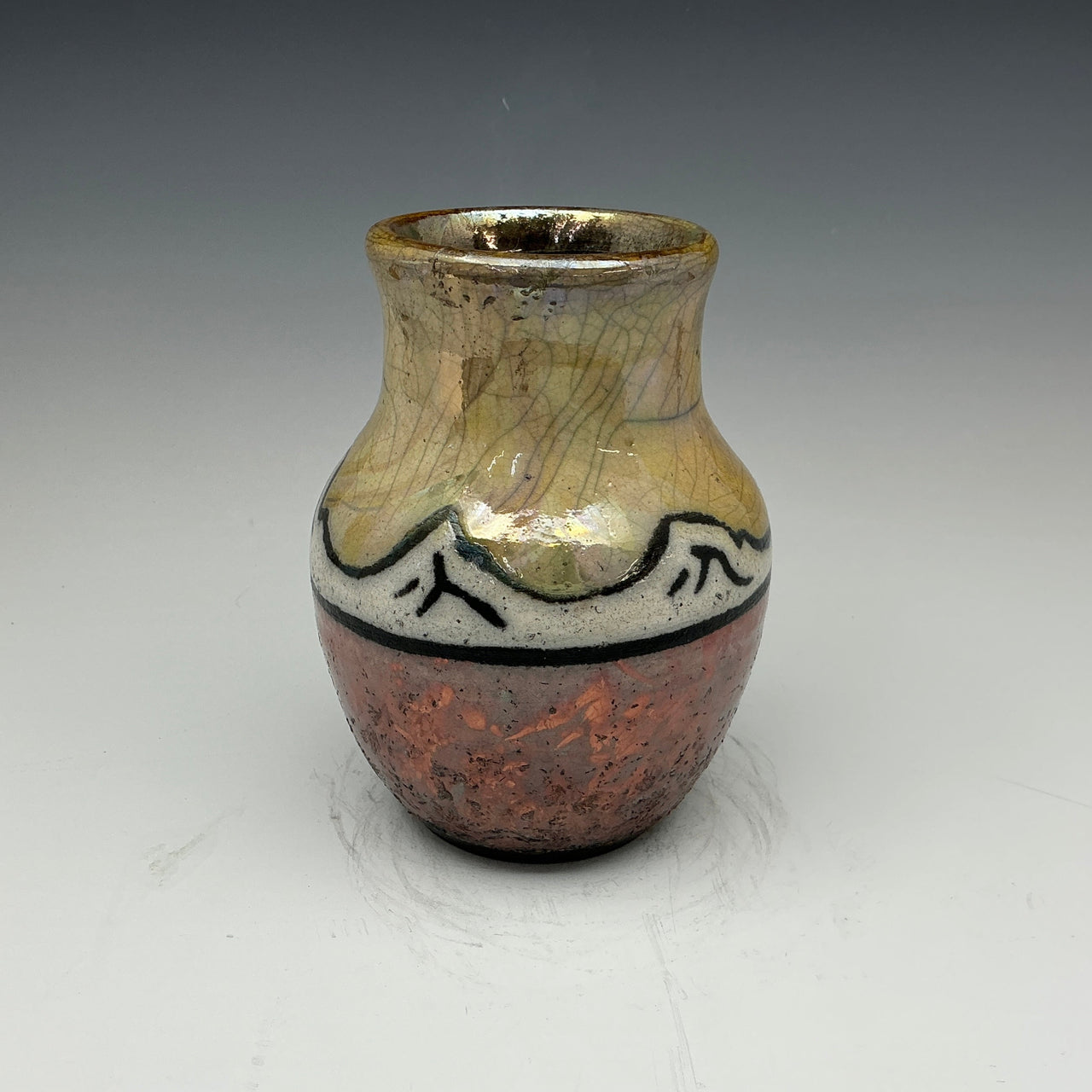 raku vase with mountains and a gold sky