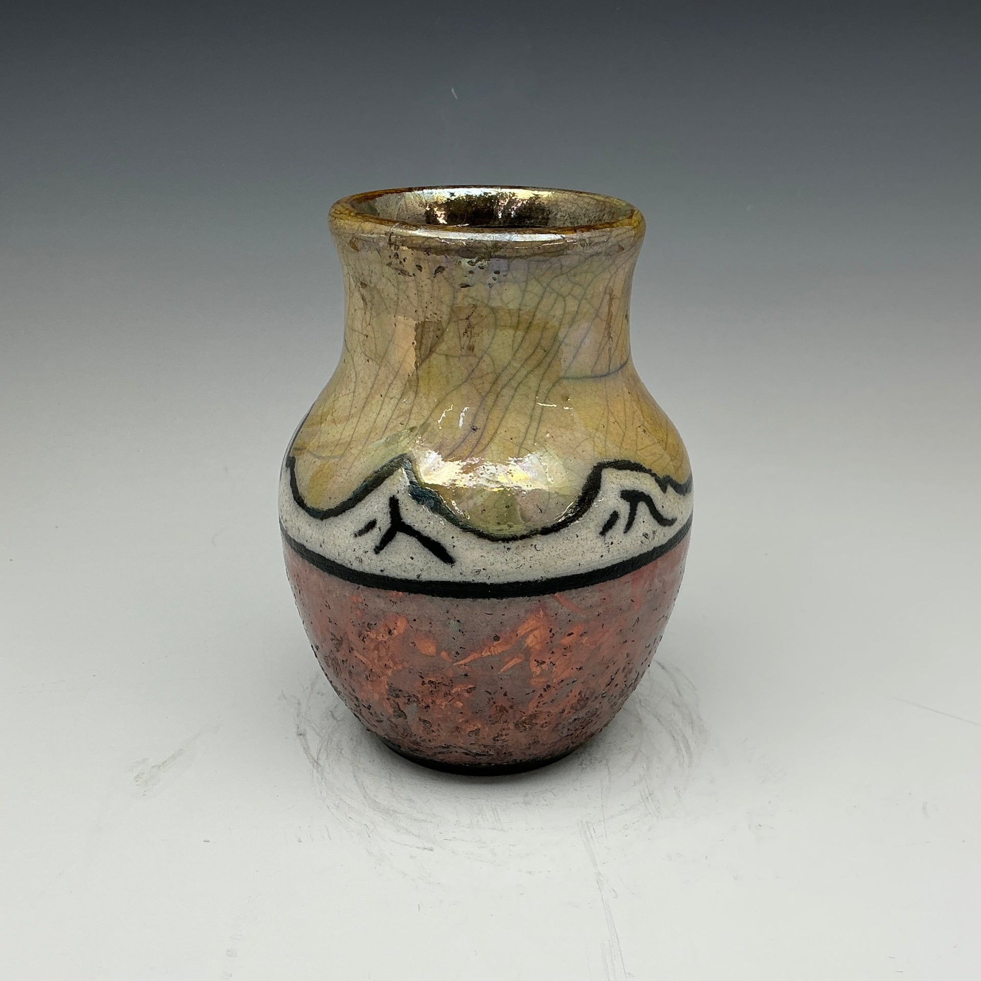 raku vase with mountains and a gold sky