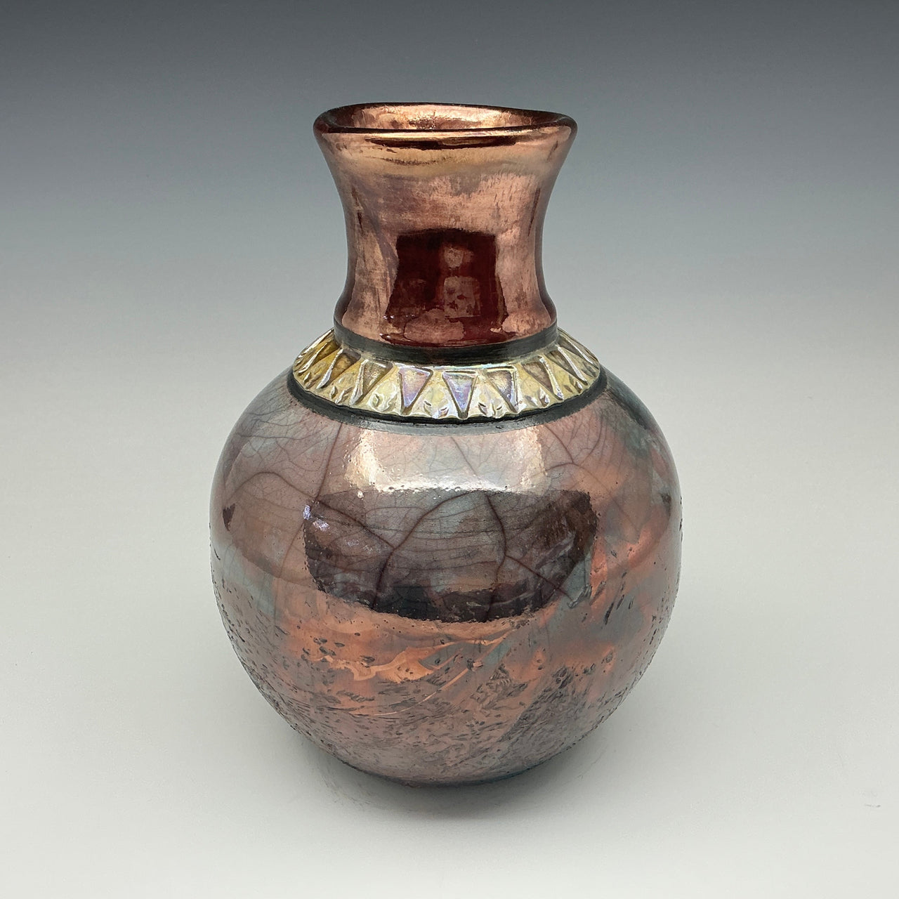 Teal and copper bottle with a gold necklace