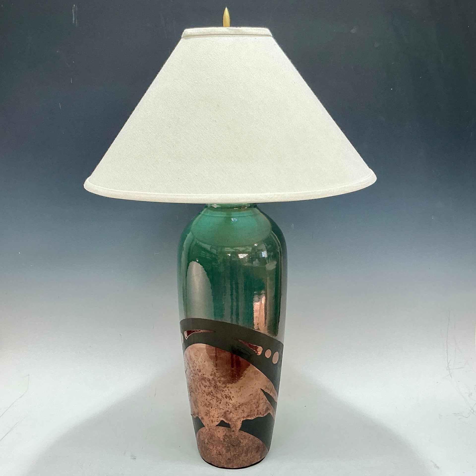 Lamp with green base and white shade on a gray background