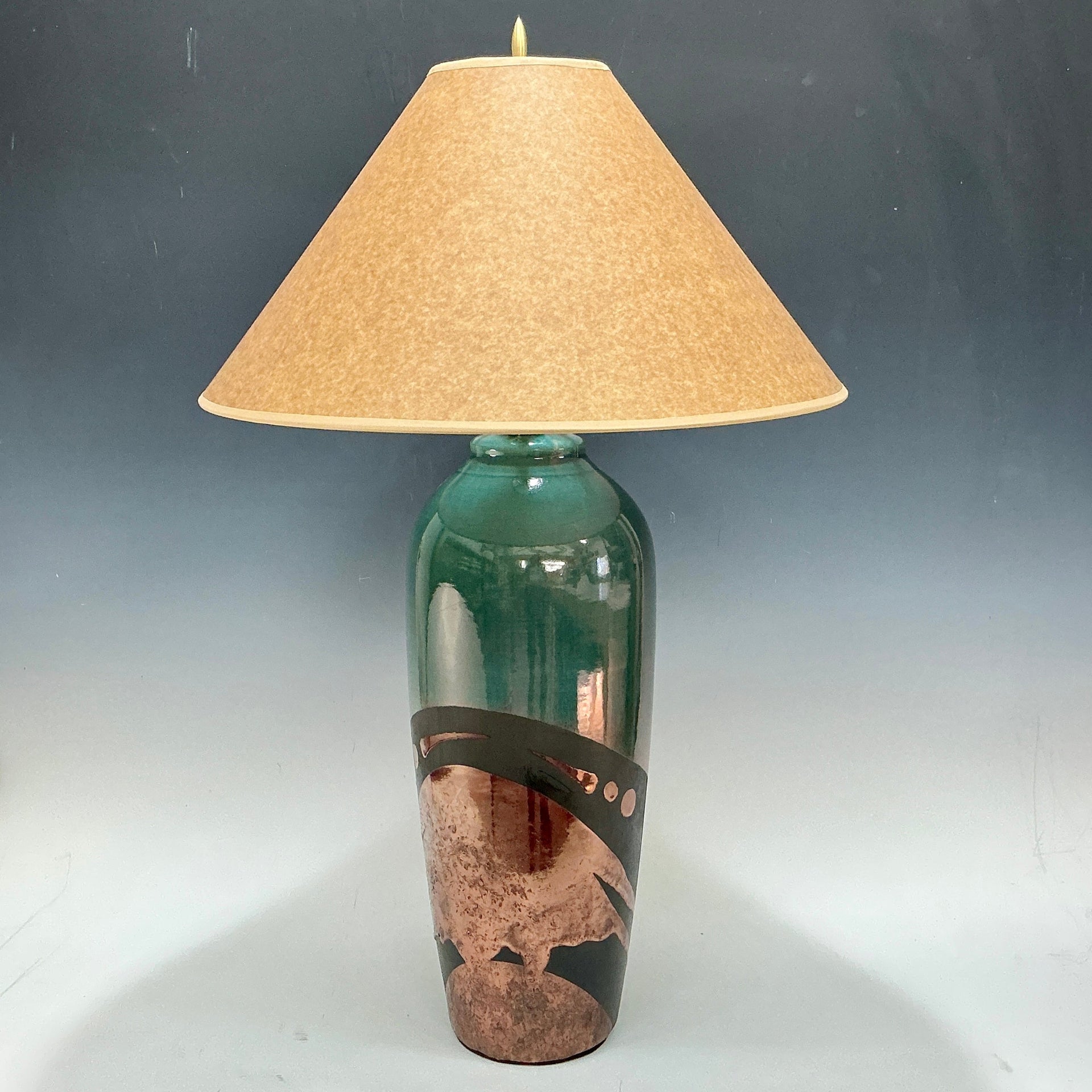 Lamp with a green base and beige lampshade on a gray background